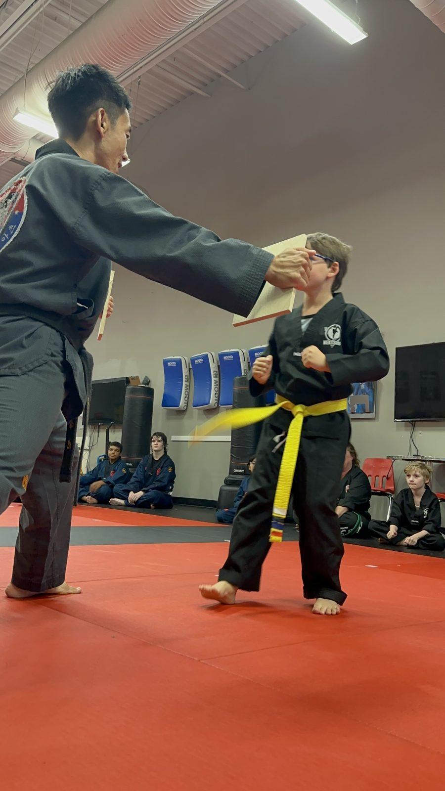 Master Jay holds a board for a young student lining up his break at NEXTStep
